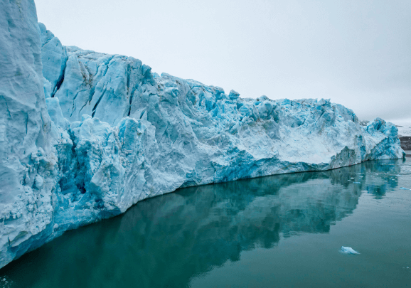Ein hoher und langer Gletscher auf Spitzbergen der sich im glatten Wasser spiegelt
